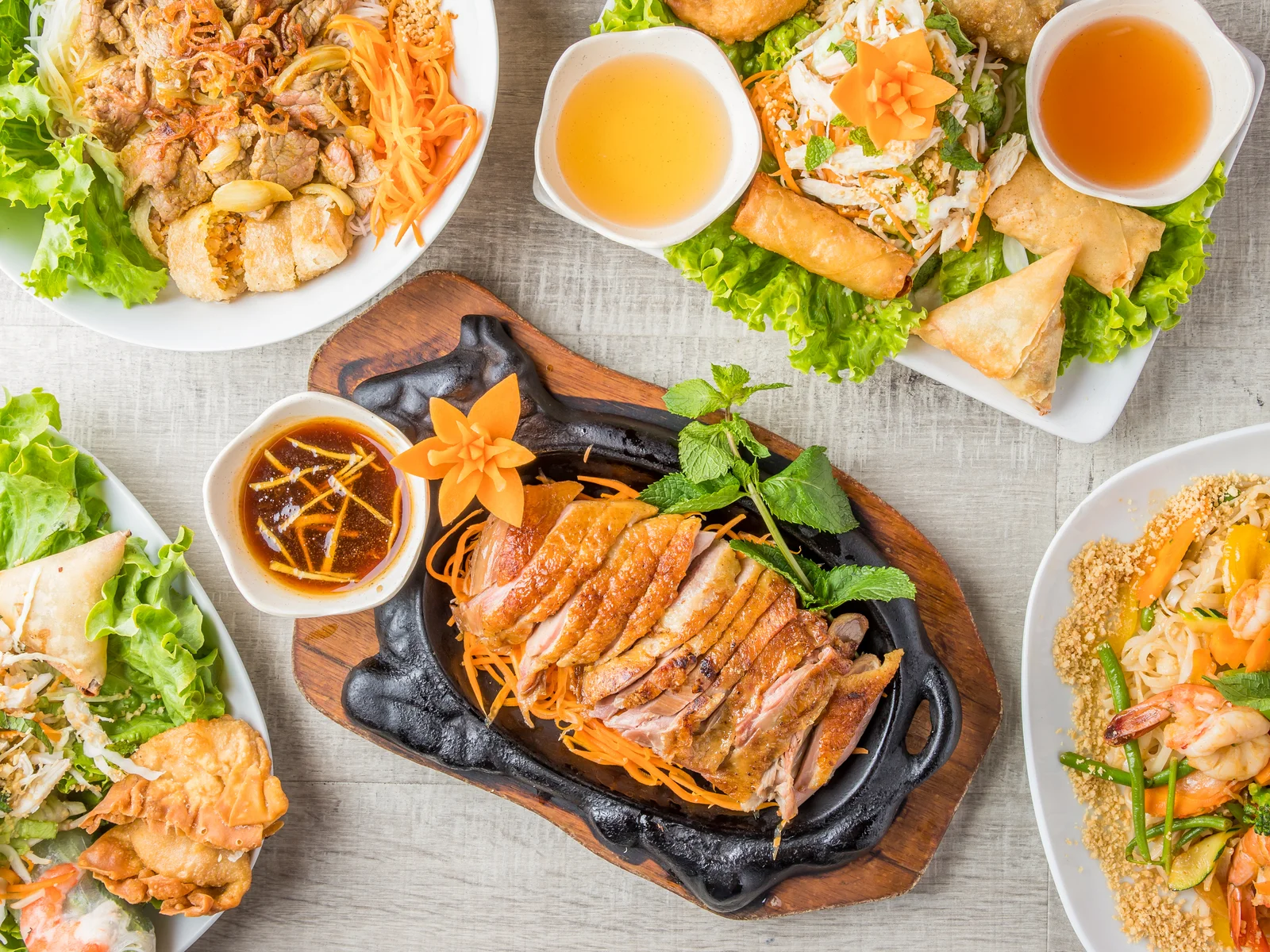 Table garnie : canard sur plaque chauffante, bo bun, nems et rouleaux de printemps