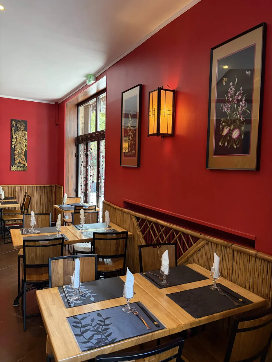 Salle de La Pagode : murs rouges, lanterne allumée, tableaux encadrés et tables dressées